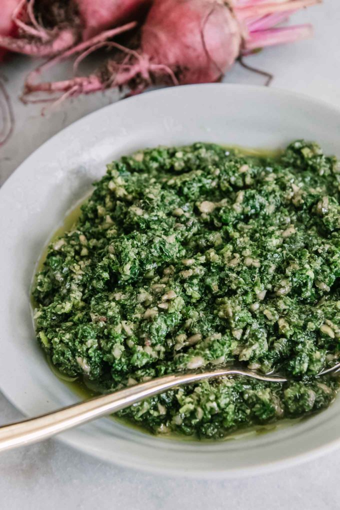 a bowl of pesto on a white table