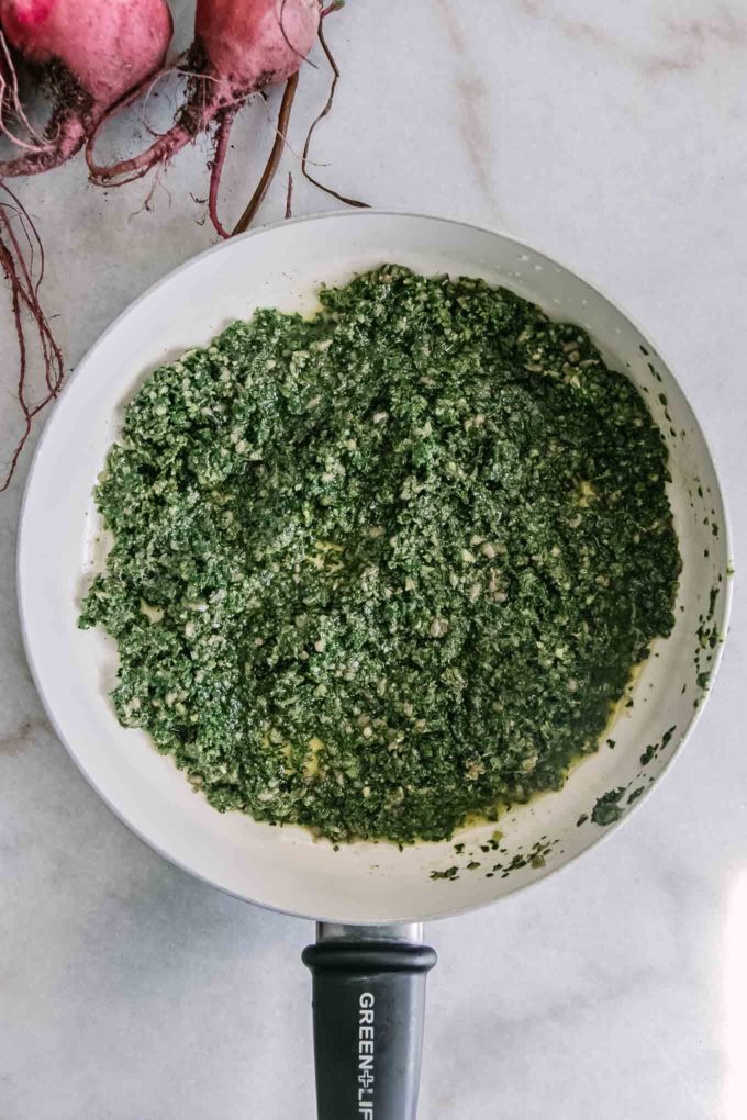 pesto made with beet leaves in a white pan on a table with red beets