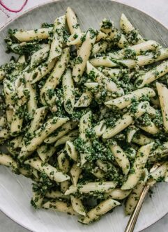 beet leaves pesto pasta on a blue plate on a white table