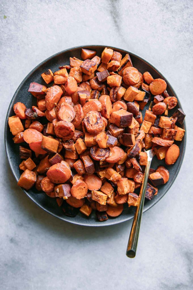 oven baked carrots and sweet potatoes on a plate on a white table