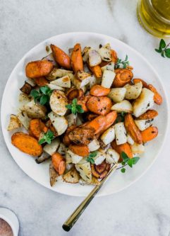 roasted turnips and carrots on a white plate with a gold fork