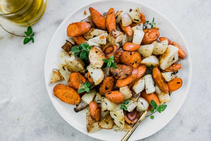 a side dish of carrots and turnips on a table with condiments