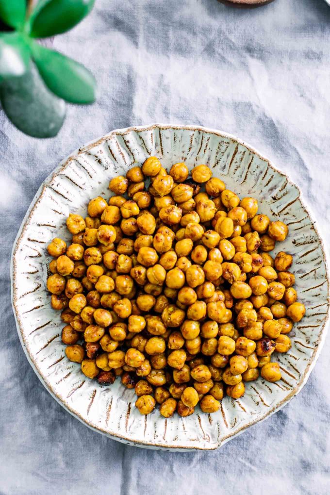 a plate of roasted garbanzo beans in a bowl on a white table