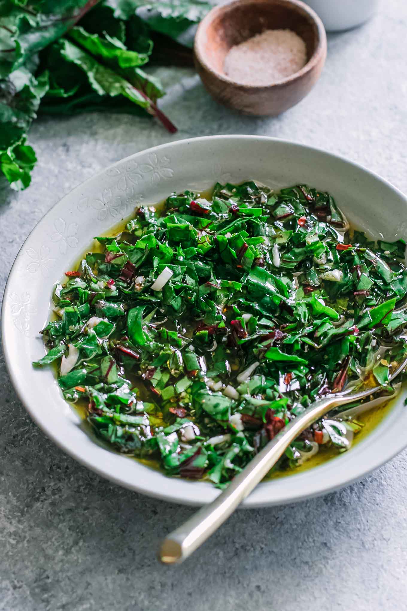 a bowl of chimichurri sauce with a gold fork on a blue table