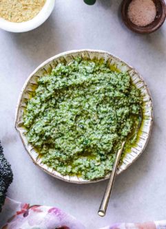 pesto made from broccoli stems in a white bowl with a gold fork