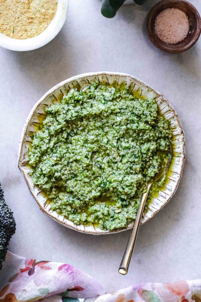 pesto made from broccoli stems in a white bowl with a gold fork