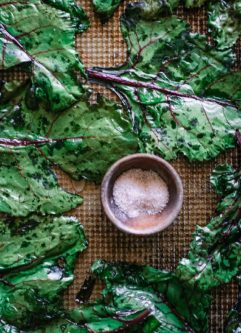 baked beet leaves on a sheet pan with a bowl of salt