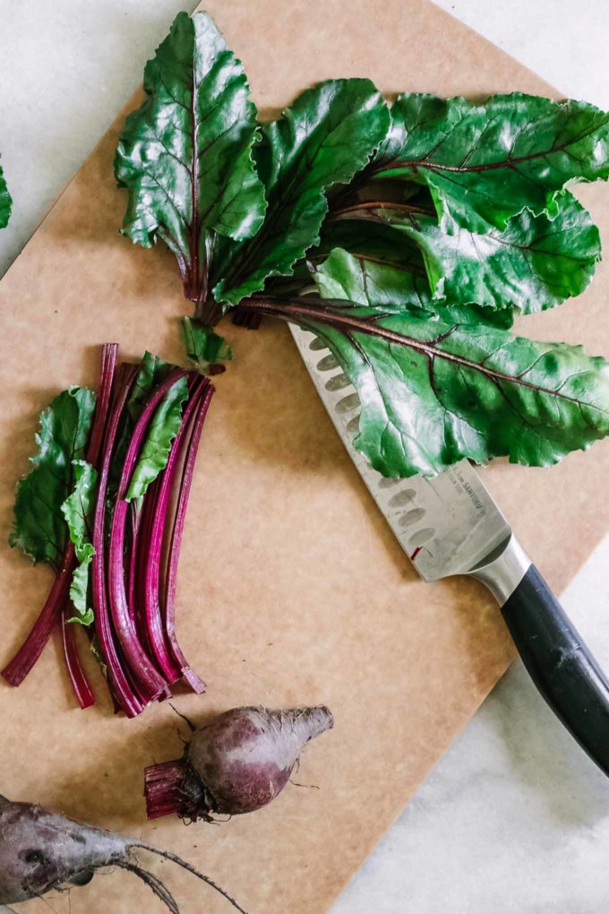 cut beet greens on a cutting board with black knife