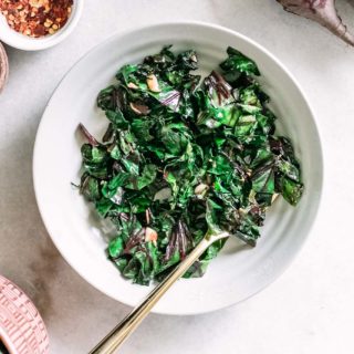 beet greens in a white bowl with a gold fork