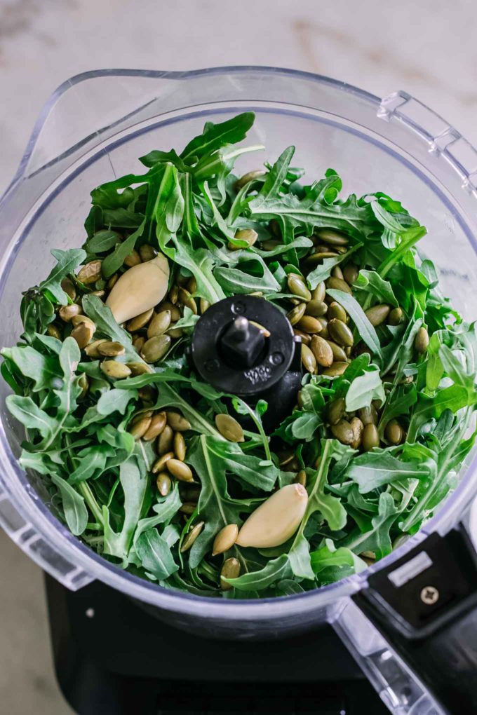 arugula, pumpkin seeds, and garlic inside a food processor