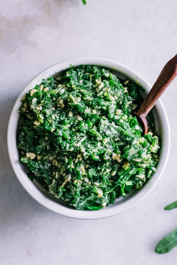 arugula pesto in a white bowl with a spoon