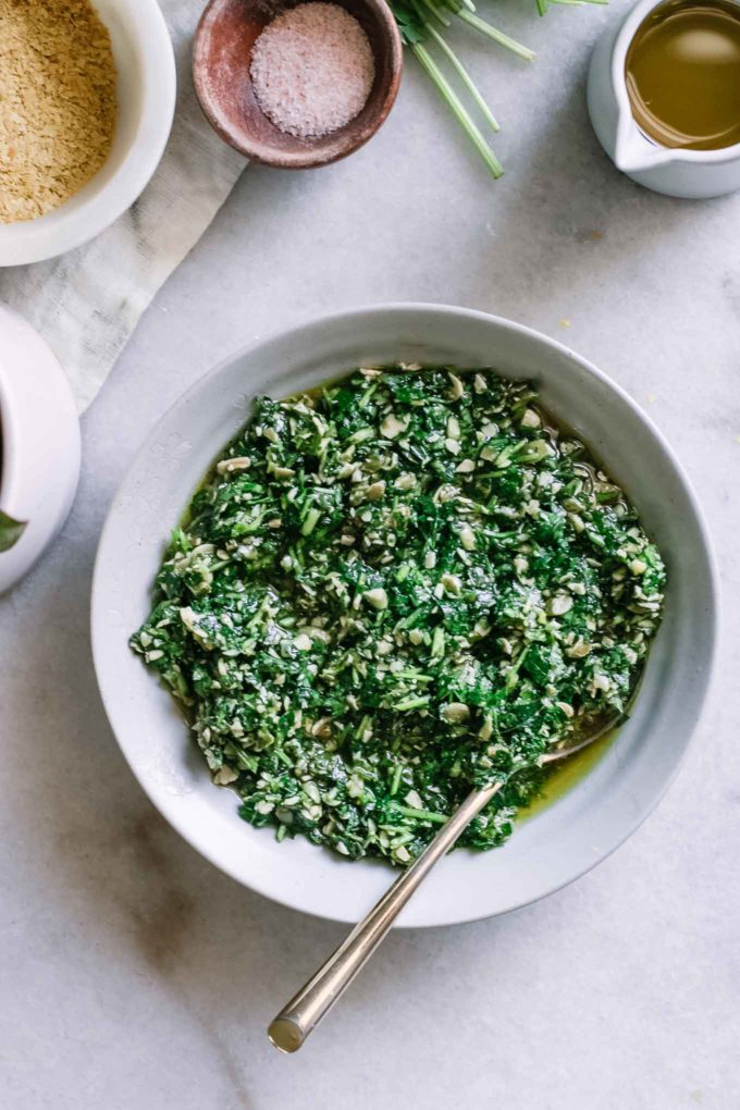 parsley pesto sauce in a blue bowl with a gold fork on a white table