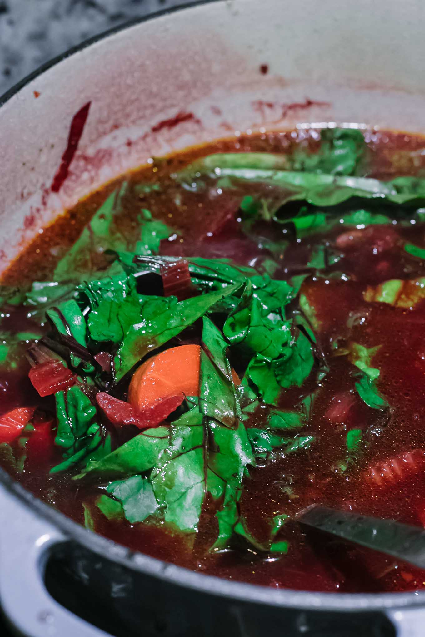 beet greens in red beet vegetable soup in a soup pot