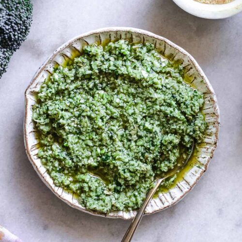 a bowl of broccoli stem pesto on a white table