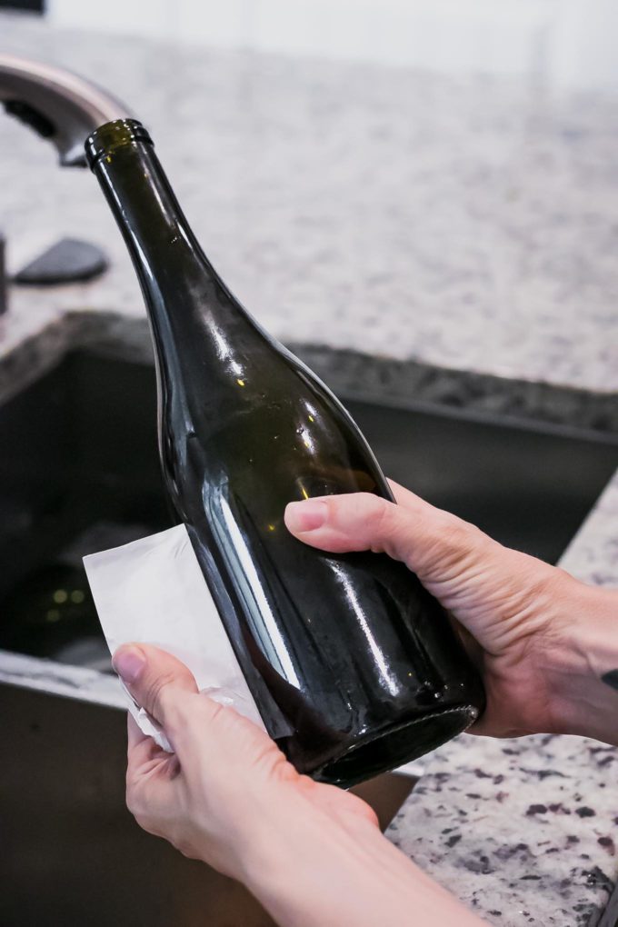 a hand peeling a label from a wine bottle