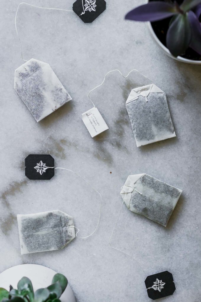 four tea bags and two succulent plants on a marble table