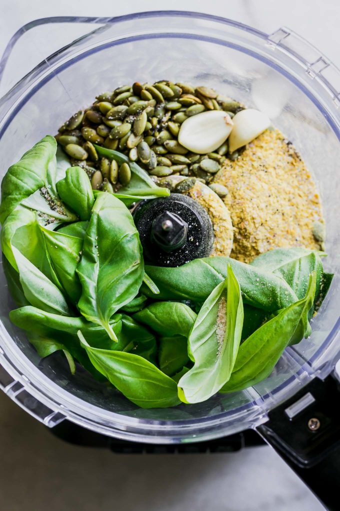 basil, pumpkin seeds, cheese, and garlic inside a food processor