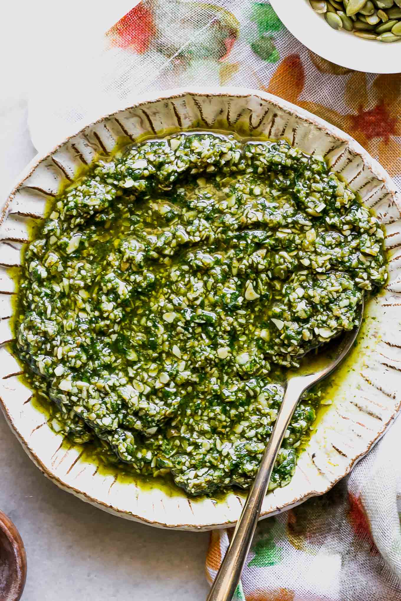 pumpkin seed pesto sauce in a white bowl with a gold fork