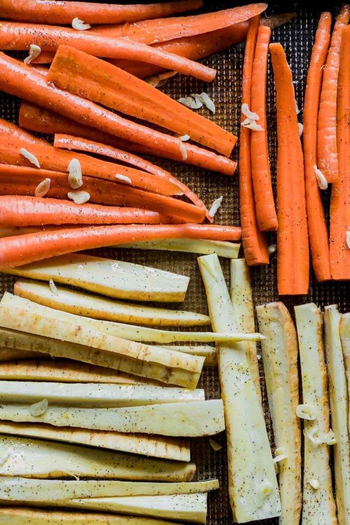 cut carrots and parsnips tossed in oil and spices on a sheet pan