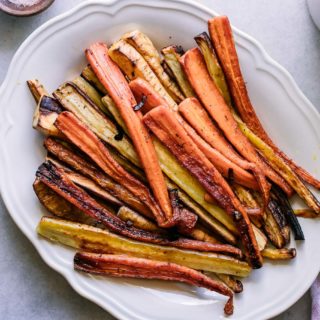 baked parsnip and carrot strips on a white plate on a marble table