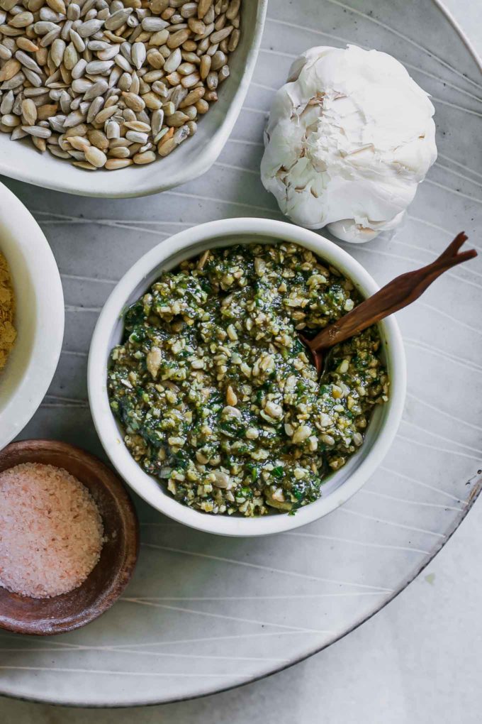 a plate with a bowl of sunflower seed pesto and a bowl of sunflower seeds