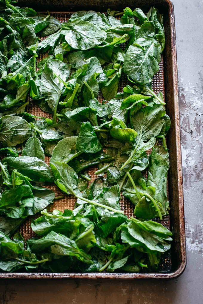 raw radish greens with oil and spices on a baking pan