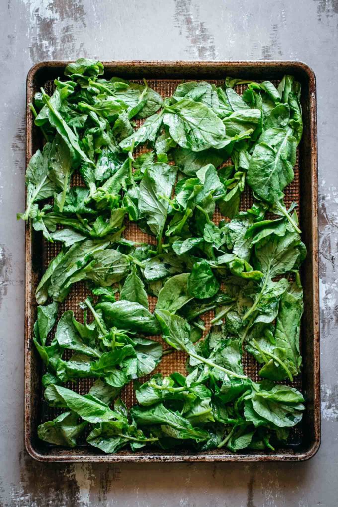 raw radish leaves on a baking pan