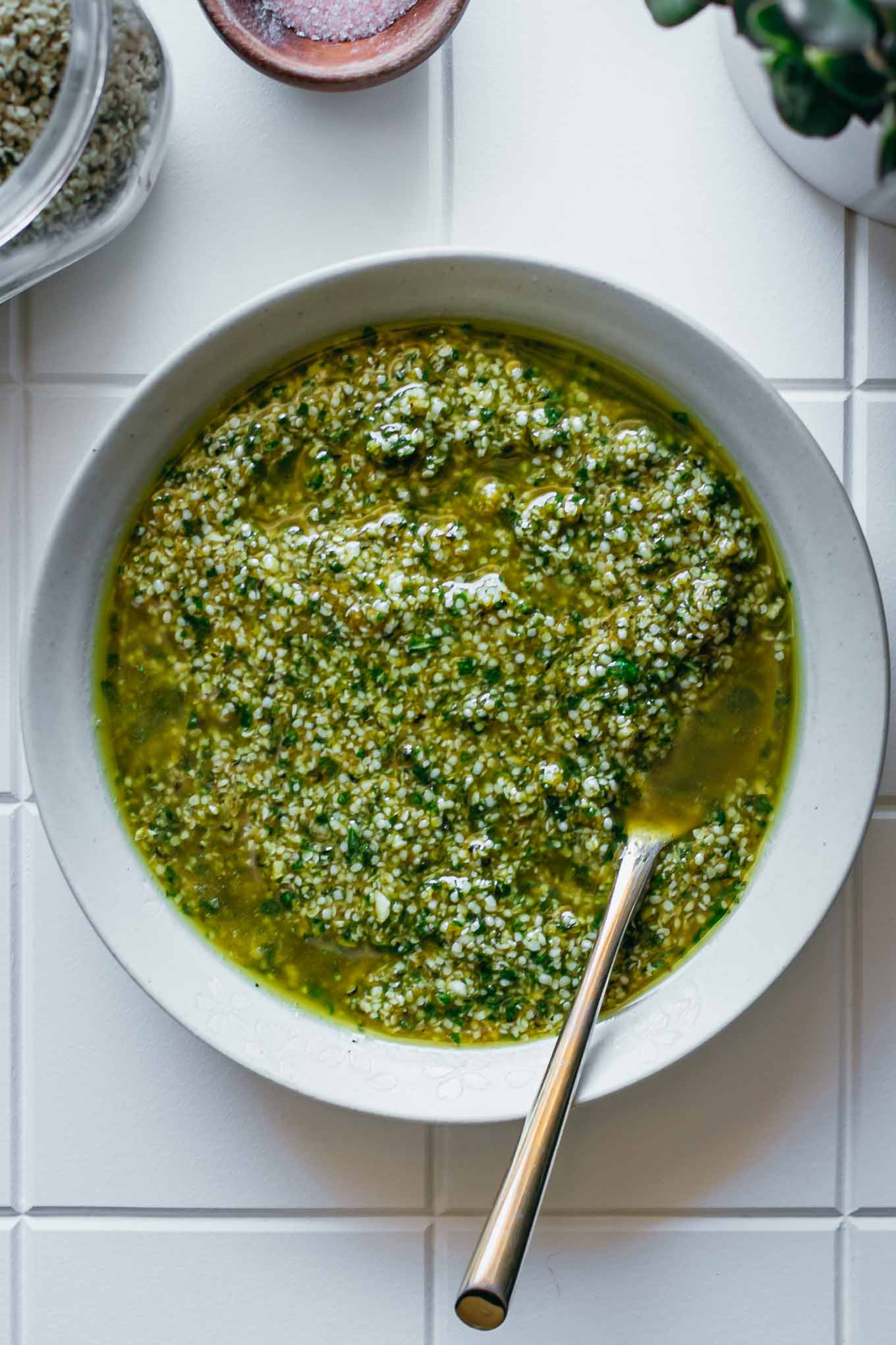 hemp seed pesto in a white bowl with a gold spoon