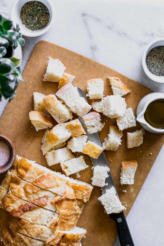 sliced and cubed sourdough bread on a cutting board with a knife