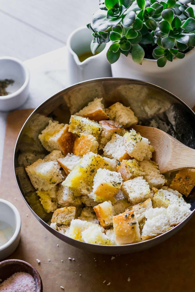 seasoned croutons in a metal bowl with a wooden spoon