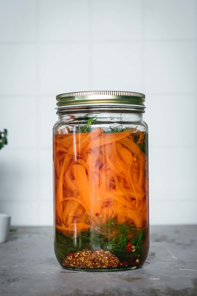 canning jar with carrot ribbons, dill, and other spices in brine