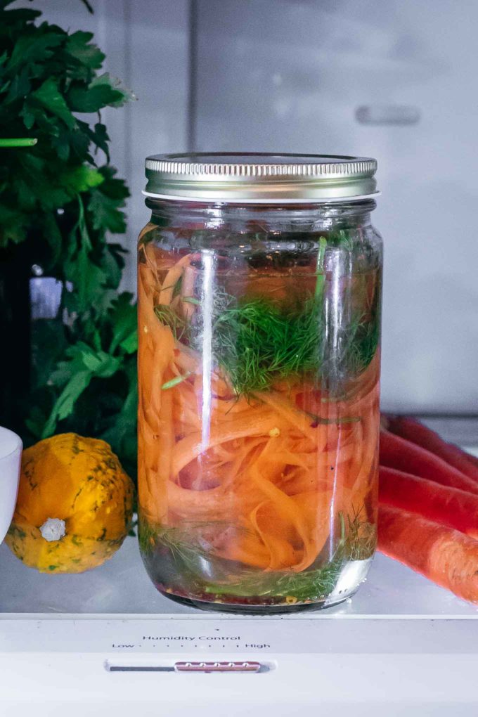cooled jar of carrot peels, dill, and other spices in the refrigerator