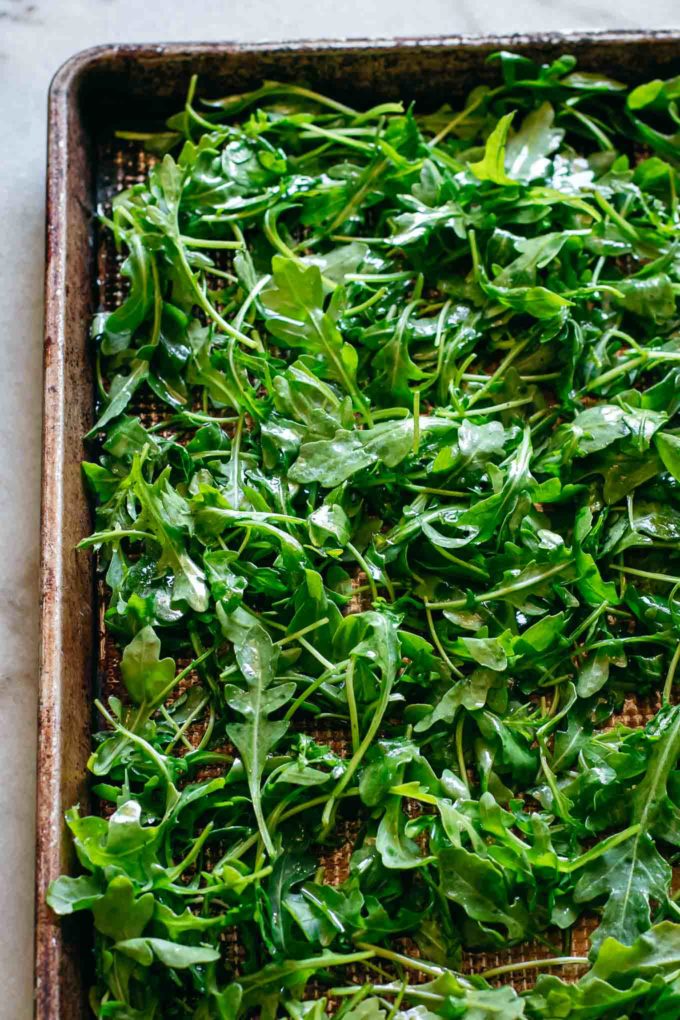 arugula leaves on a baking sheet before baking