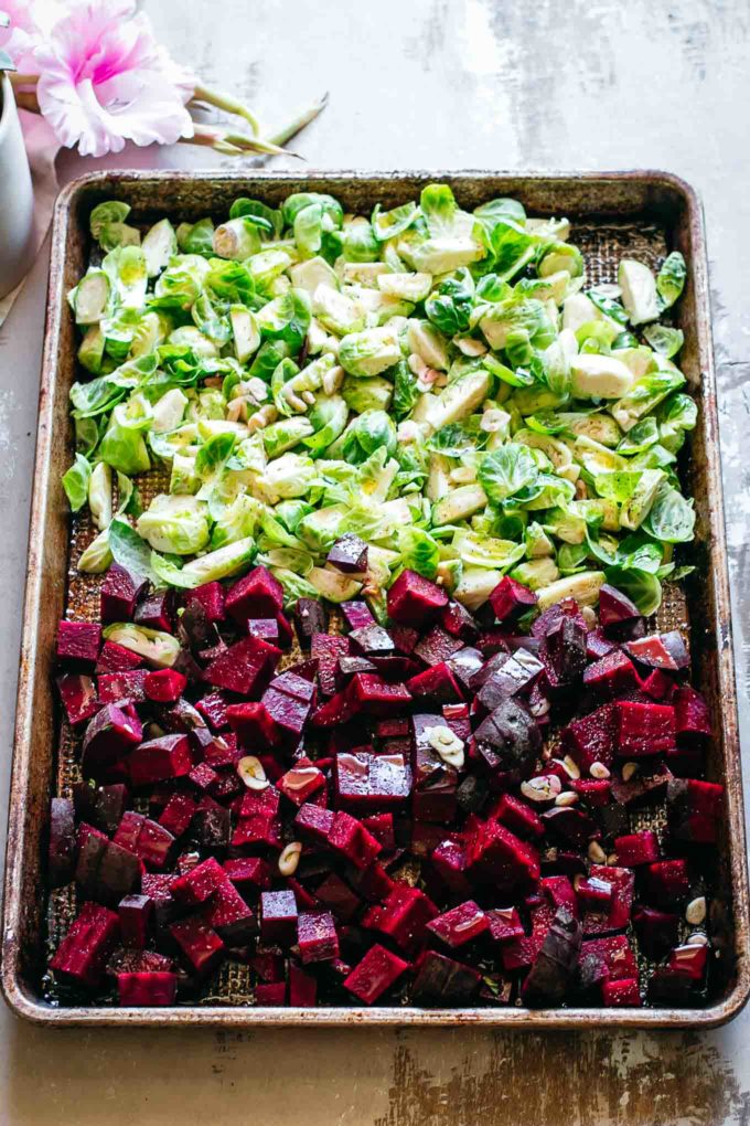 uncooked chopped beets and brussels sprouts on a baking pan