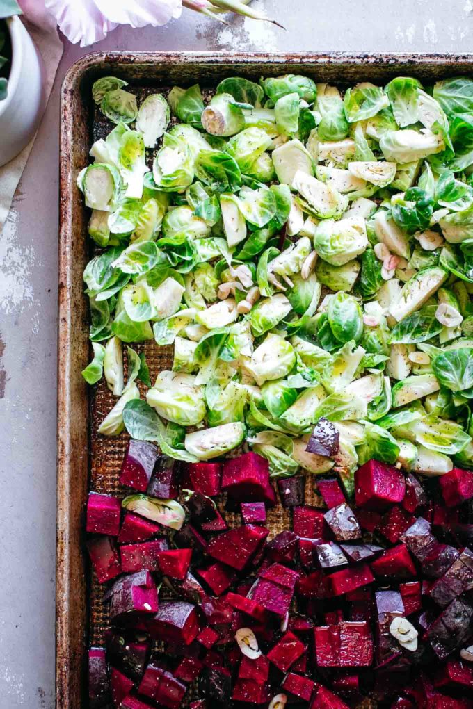 seasoned uncooked chopped red beets and brussels sprouts on a sheet pan