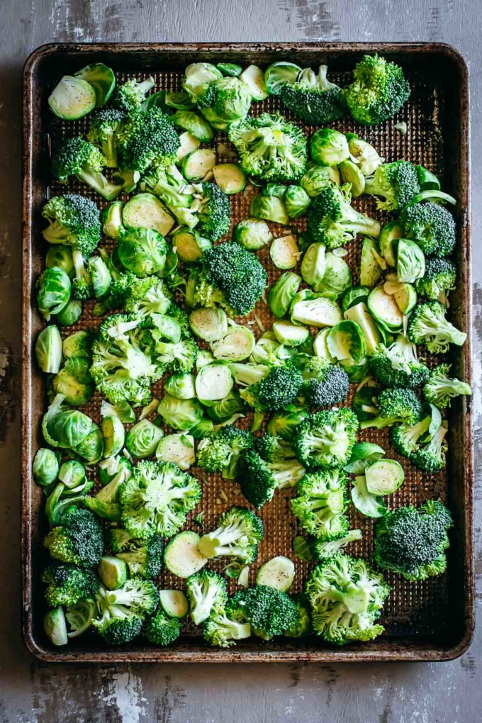 cut and seasoned brussels sprouts and broccoli on a roasting pan