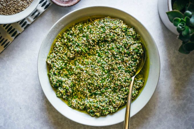 pesto with sesame seeds in a bowl on a white table