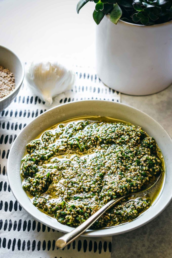 pesto sauce with sesame seeds in a bowl on a table with a colored napkin