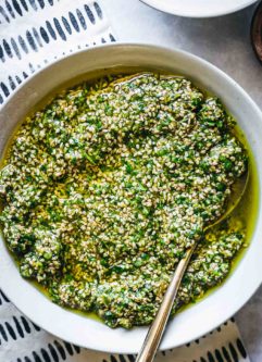 sesame seed pesto in a white bowl with a gold spoon