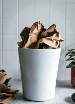 crumpled paper bag in a white ceramic bin on a countertop