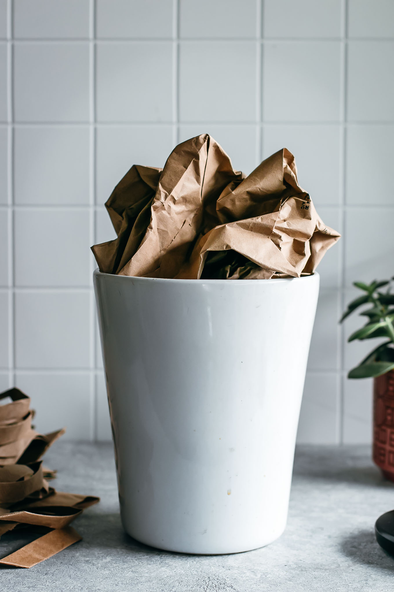 crumpled paper bag in a white ceramic bin on a countertop