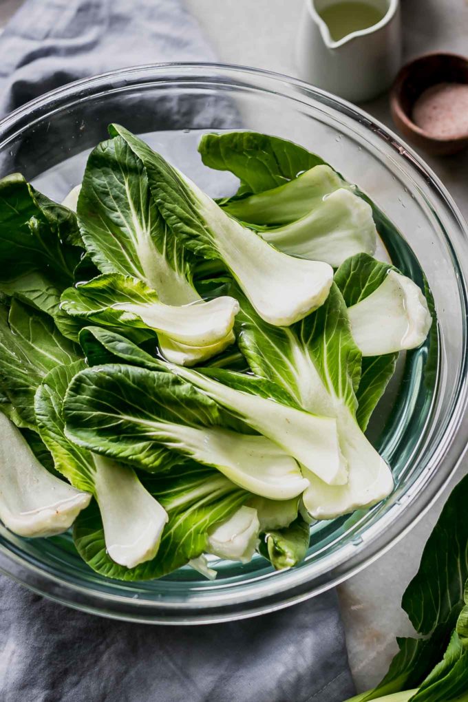 bok choy leaves in a bowl of water on a table
