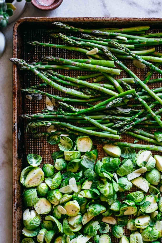 chopped raw brussels sprouts and asparagus arranged on a baking sheet