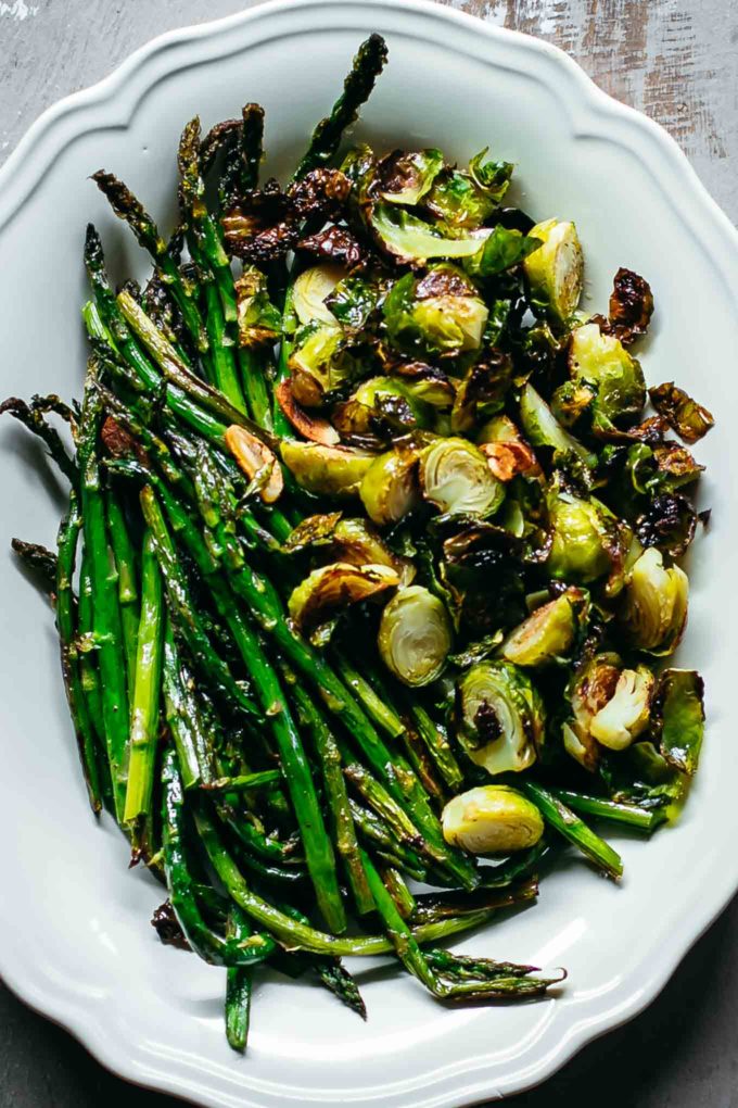 roasted asparagus and brussels sprouts in a white serving dish