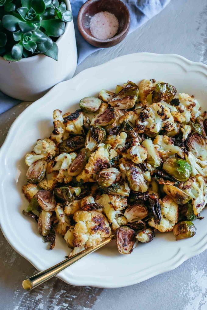 roasted brussels sprouts and cauliflower on a white plate on a wood table