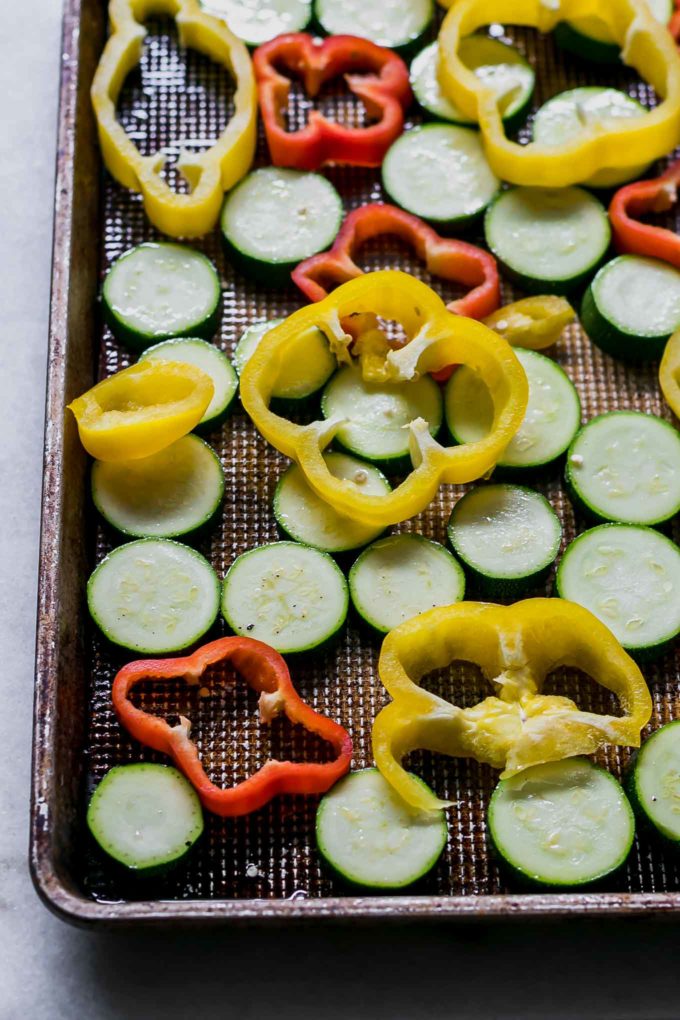 sliced bell peppers and zucchini on a baking sheet