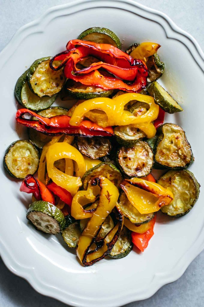 roasted zucchini and peppers on a white plate on a white countertop