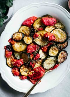 roasted tomatoes and zucchini on a white serving plate