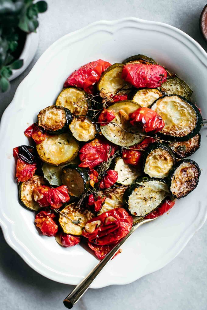 roasted tomatoes and zucchini on a white serving plate