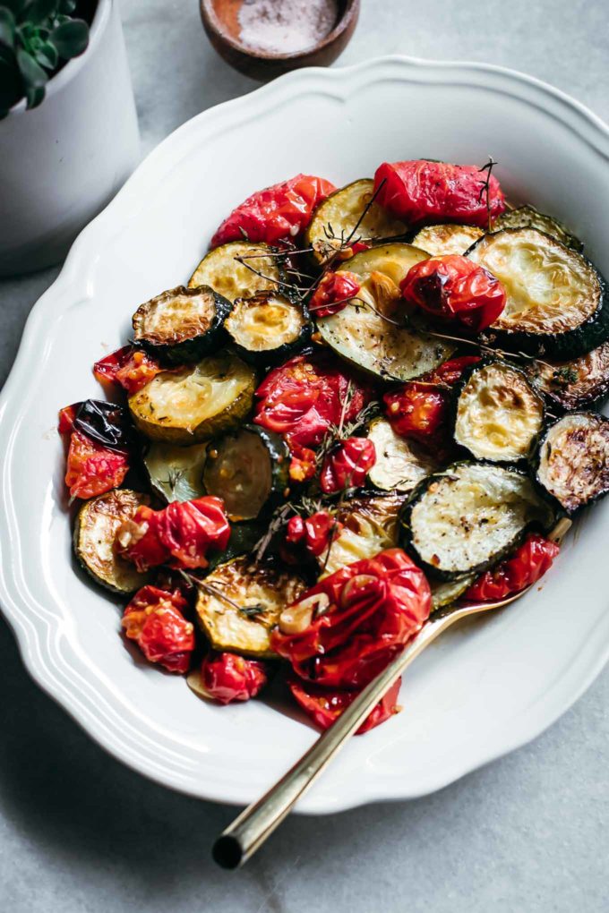roasted tomatoes and zucchini slices on a plate on a white countertop